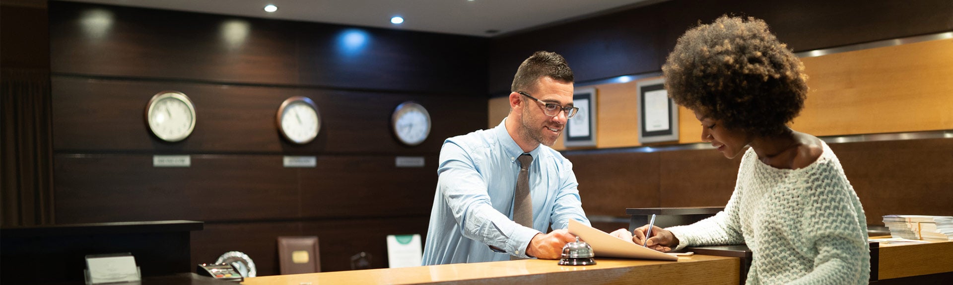 Image of male hotel receptionist checking in a female guest