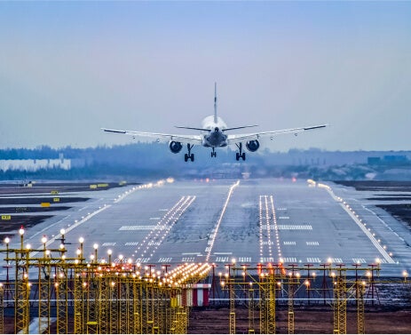 Photo showing a rear vantage point of a commercial airplane lifting off a runway to take flight.